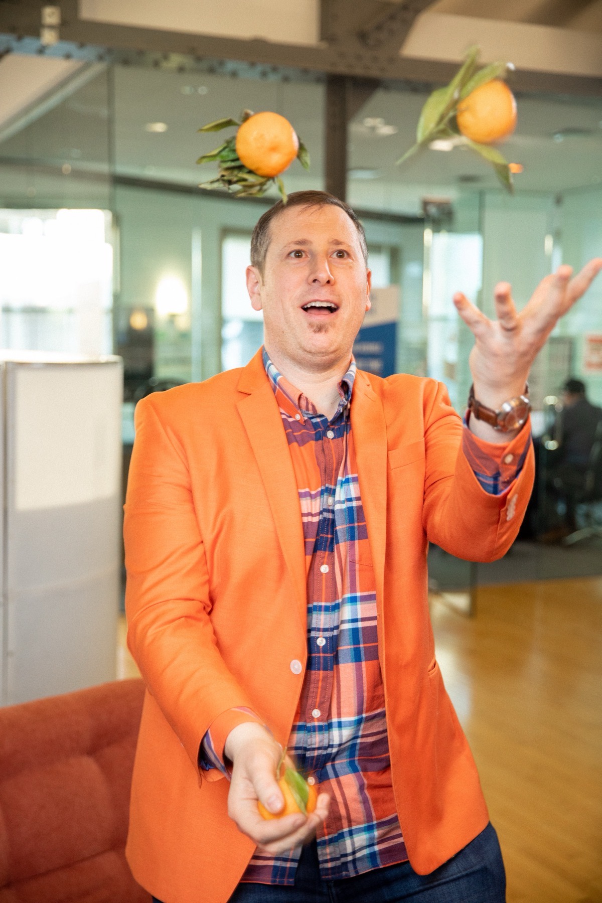 Dan Golden juggling two oranges in an orange blazer
